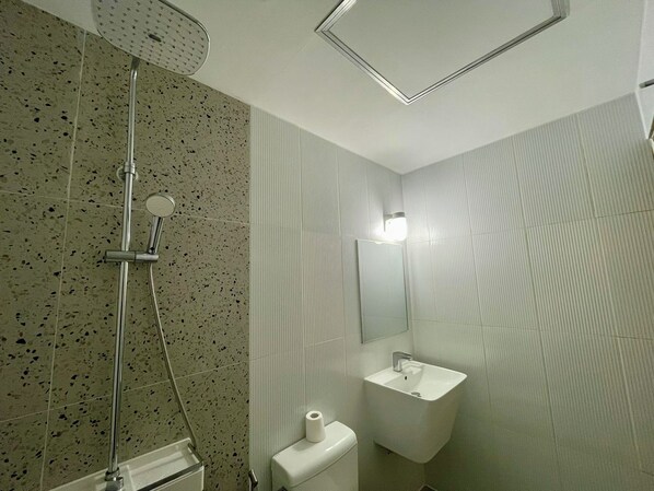 A bathroom with a shower, toilet, and sink.