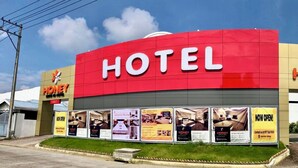 Un hotel llamado 'Honey' con una fachada destacada en rojo y amarillo, múltiples habitaciones incluyendo una para automovilistas, y varios banners promocionales.