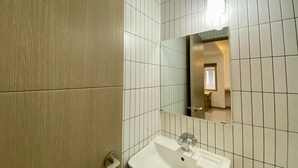 Un baño con un lavamanos blanco, un espejo y una puerta.