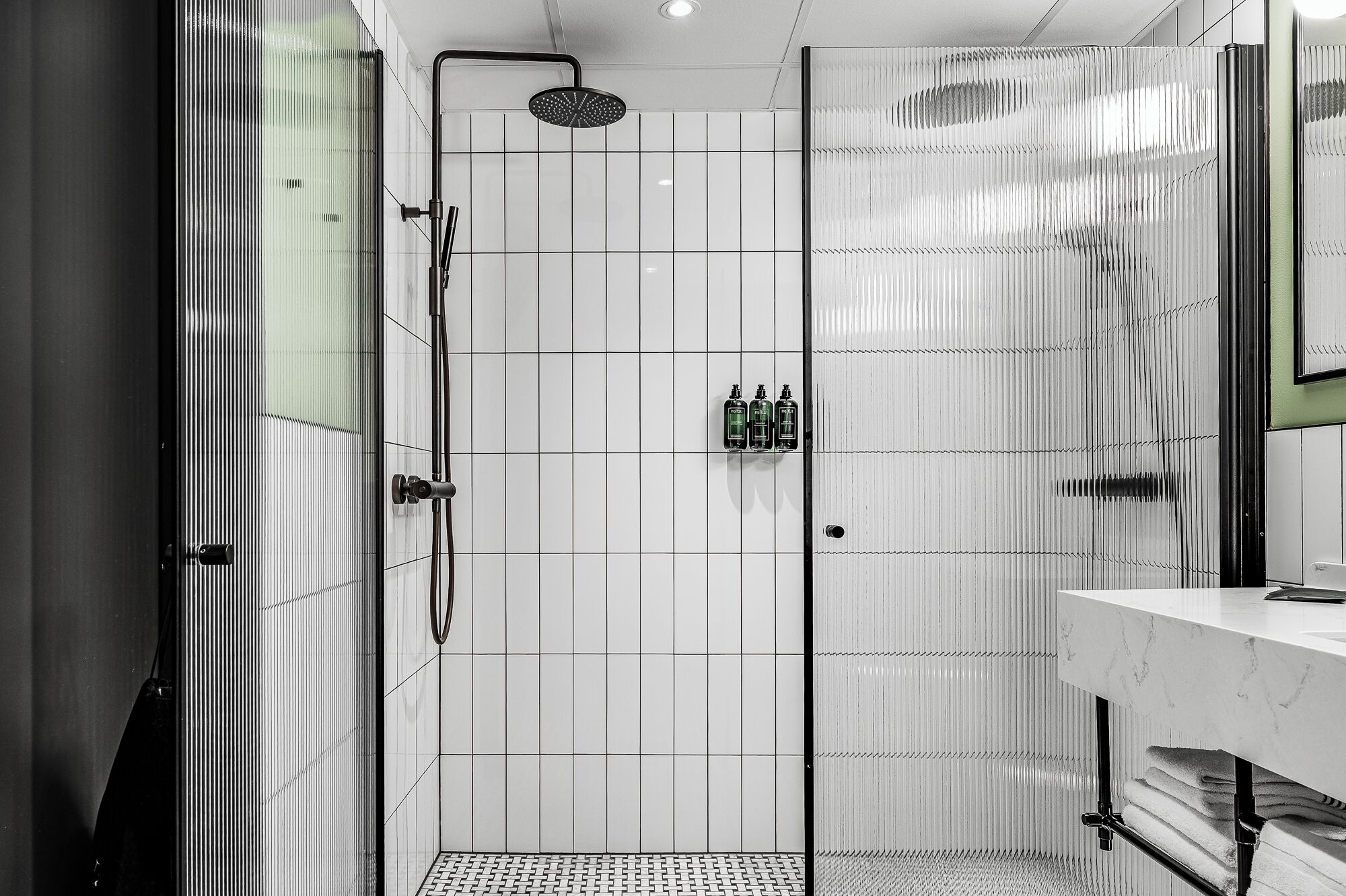 A modern bathroom with a glass-enclosed shower, a marble sink, and a towel rack.