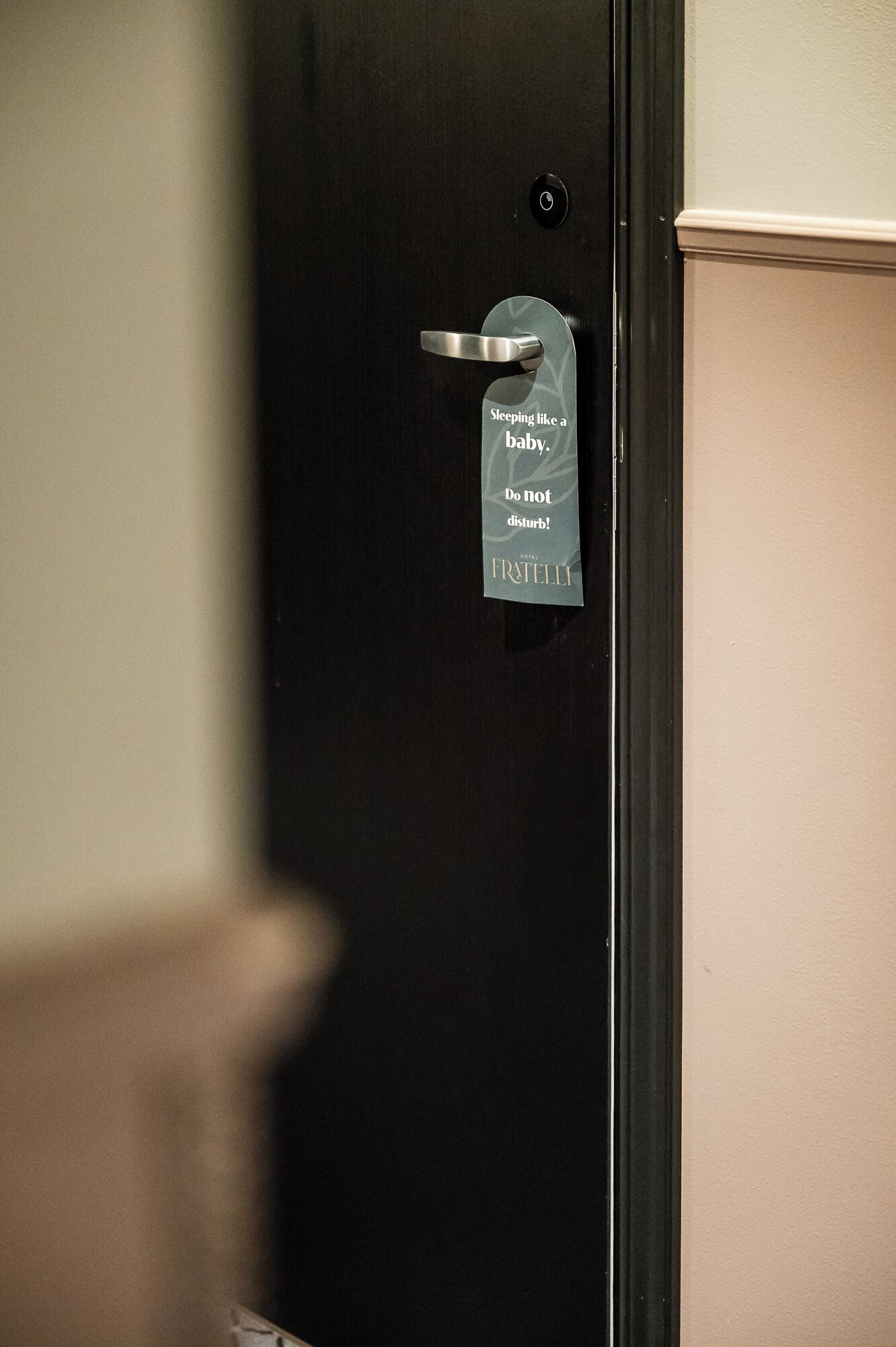 A hotel room door with a sign that reads "Sleeping like a baby. Do not disturb."