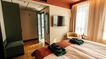Una habitación de hotel con una cama, una silla, un televisor y un espejo.