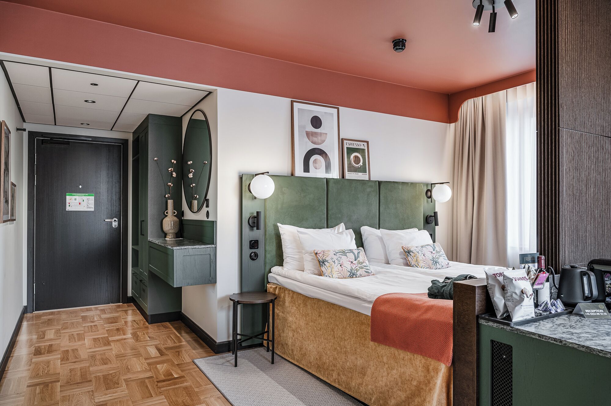 Ein Hotelzimmer mit Bett, Schreibtisch, Spiegel und Rezeption.