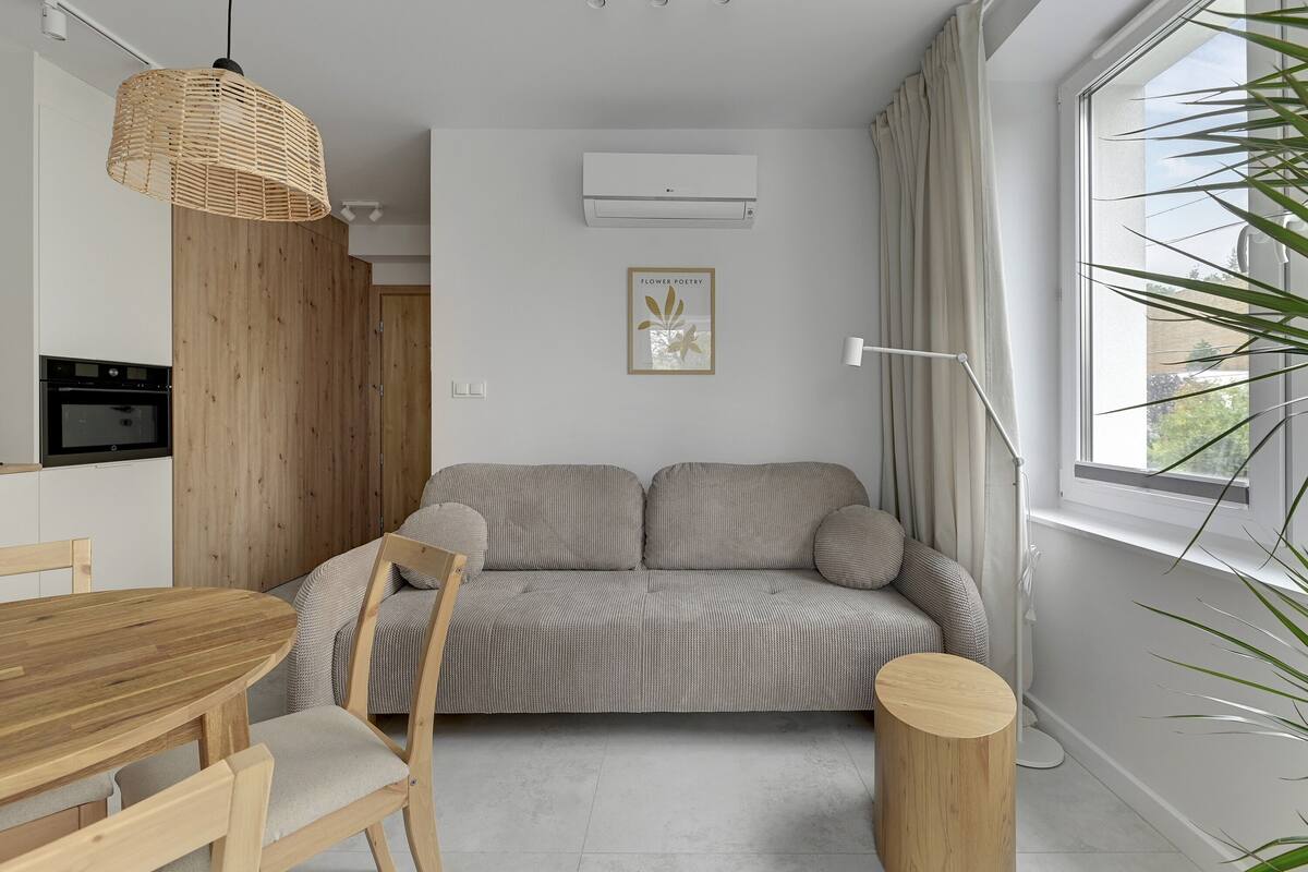 Een moderne woonkamer met een bank, een eettafel en een hanglamp.