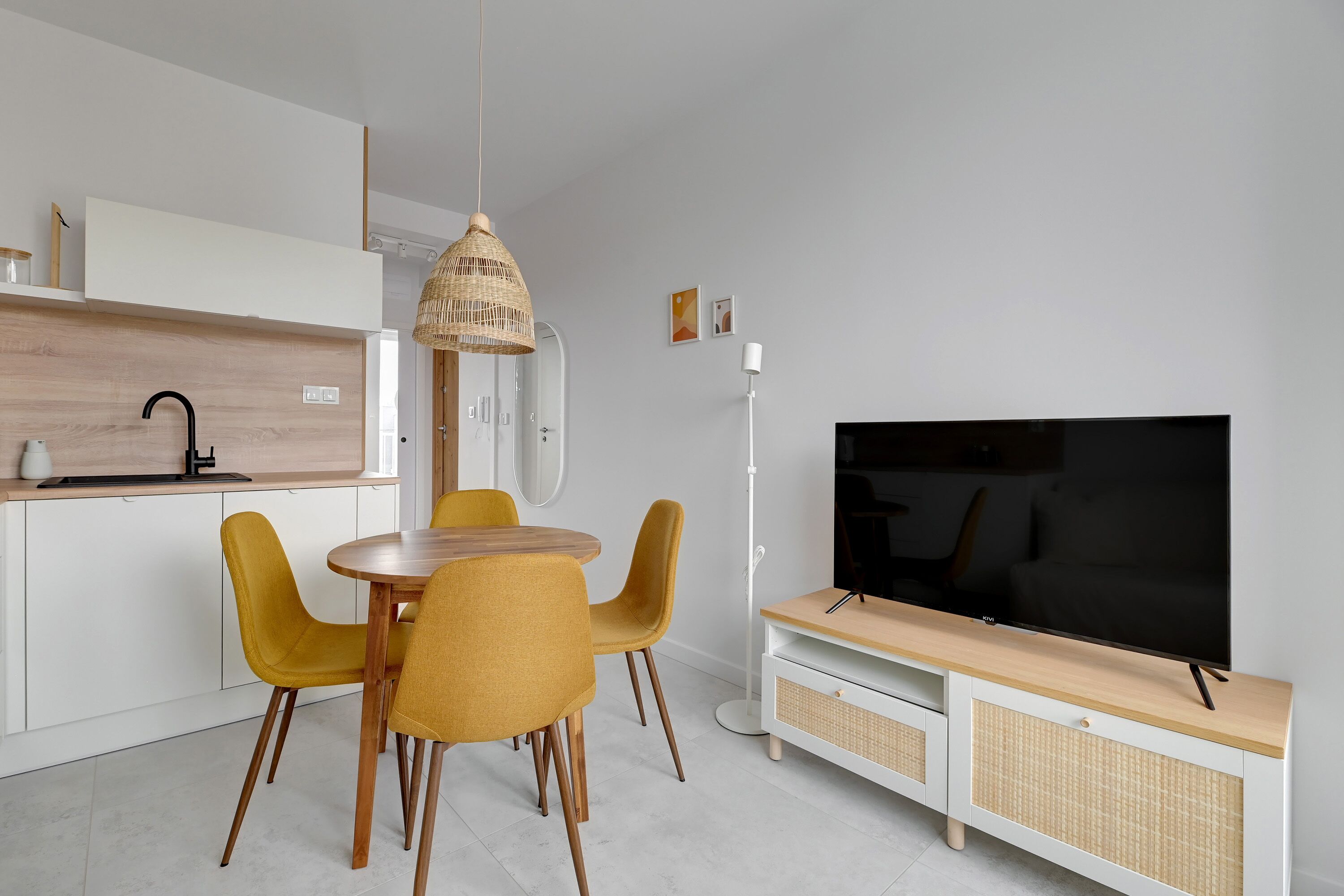 Una cocina moderna con comedor, televisor y lámpara colgante.