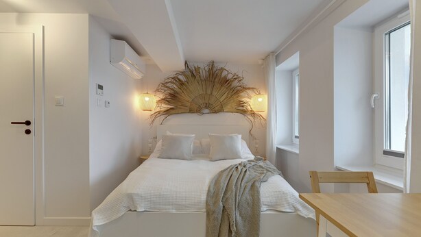 A bedroom with a bed, a wooden table, a chair, and a decorative wall piece.