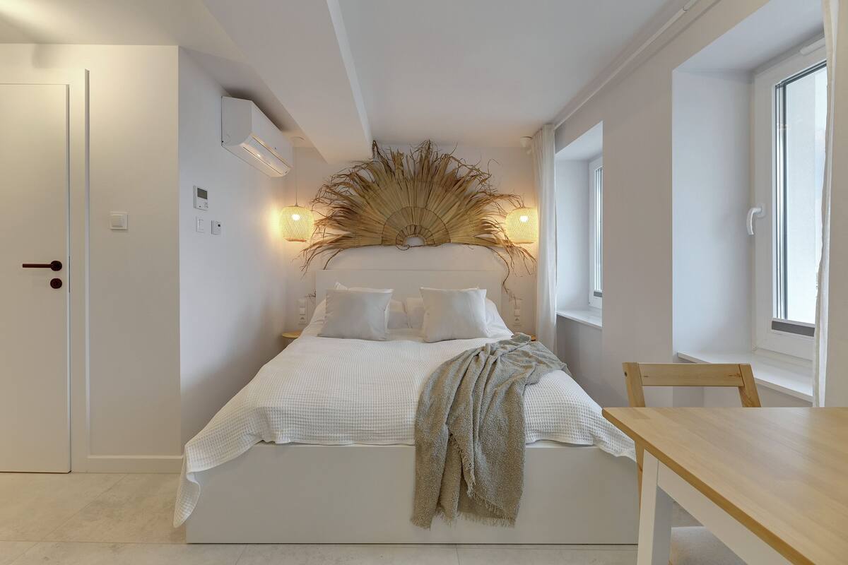 Een slaapkamer met een bed, een houten tafel, een stoel en een decoratief wandobject.