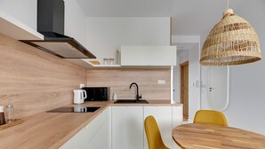 A modern kitchen with white cabinets, a wooden countertop, a black microwave, a sink, and a yellow chair.