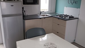 Ett kompakt kök med kylskåp, mikrovågsugn, diskho, spis och ett bord med en dekorativ tallrik.