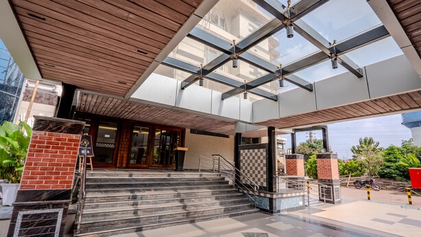A hotel entrance with a wooden ceiling, glass panels, and a staircase leading to the lobby. - HOTEL LUCKY INDIA  (Bhubaneshwar)
