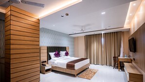 A modern hotel room with a large bed, a desk, a chair, and a TV mounted on the wall. - HOTEL LUCKY INDIA  (Bhubaneshwar)