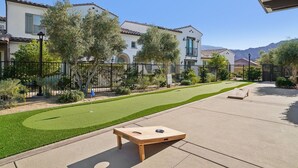 A residential area with a well-maintained lawn, a wooden board game table, and a house with a tiled roof.