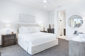 Ein modernes Schlafzimmer mit einem großen Bett, Nachttischen, einem Spiegel und Kunstwerken an den Wänden.