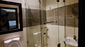 Un bagno moderno con doccia vetro, water e lavandino.