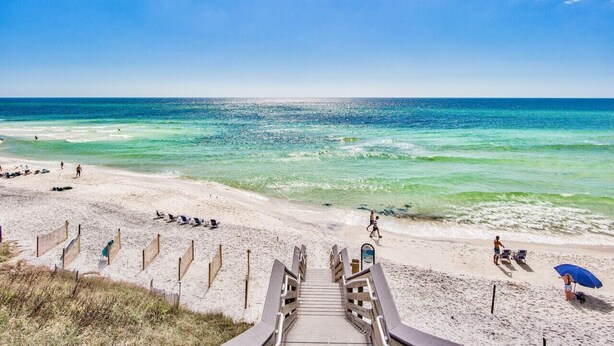 A beach with a wooden staircase leading to the shore, clear turquoise water, and a few people on the sand. - Charming 3BR Home on 30A – Golf Cart Included, 5 Min to Beach (Santa Rosa Beach)