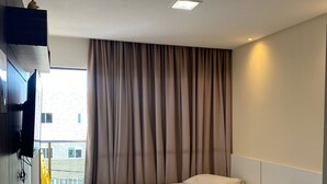 A hotel room with two beds, a TV mounted on the wall, and a balcony with a yellow chair. - Manawa Beach Flat by All (Ipojuca)