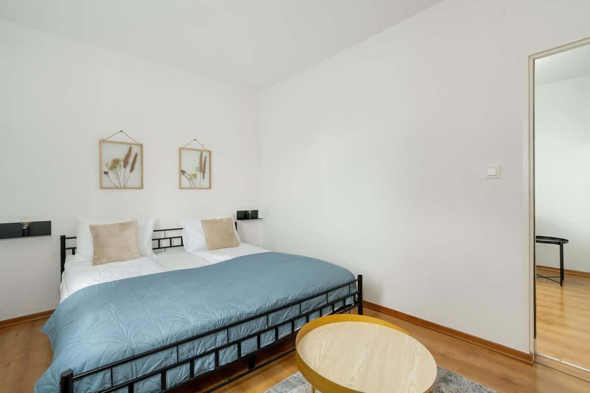 Une chambre à coucher comprenant un lit, deux cadres photos accrochés au mur, une table de chevet et une chaise.