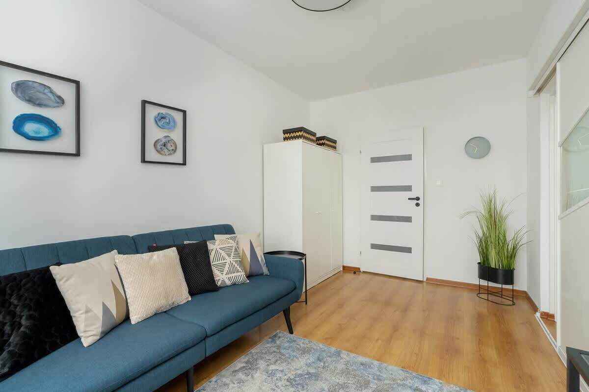A modern living room with a blue sofa, a small rug, and a white wardrobe.
