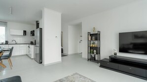 Eine moderne Küche mit weißen Schränken, einem eingebauten Ofen und einem Essbereich mit Tisch und Stühlen.