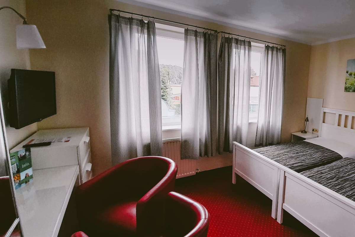 A hotel room with a bed, a desk, a chair, and a window with curtains.