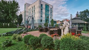 Un patio con mesas al aire libre, una estatua y un edificio con ventanales amplios.