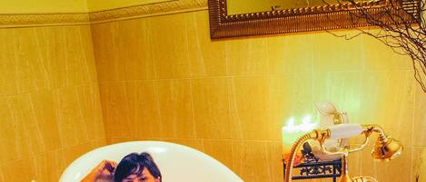 A bathtub with a golden faucet and a flower on the floor.