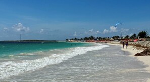 A beach with clear turquoise water, a sandy shore, and a few people walking. - Classy 2-bedroom with pool and beach Orient Bay (Saint-Martin)