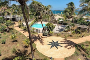 Um resort com piscina, palmeiras e um design em formato de estrela no chão.