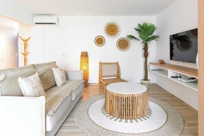 A living room with a sofa, a round coffee table, a TV, and decorative wall art.