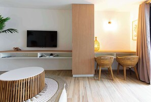 Ein modernes Wohnzimmer mit Flachbildfernseher, Holzmöbeln, Korbstühlen und einer Stehlampe.