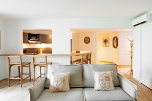 A modern living room with a sofa, chairs, a dining table, and a kitchen area with a microwave. - Classy 2-bedroom with pool and beach Orient Bay (Saint-Martin)