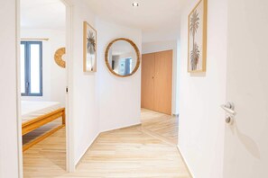 A hallway with a wooden floor, a bed, a wardrobe, and a mirror with a decorative frame. - Classy 2-bedroom with pool and beach Orient Bay (Saint-Martin)