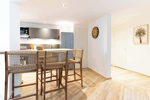 Una cocina moderna con comedor, suelo de madera y un reloj en la pared.