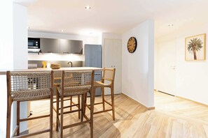Eine moderne Küche mit Essbereich, Holzboden und einer Uhr an der Wand.