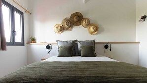 A bedroom with a large bed, a wooden headboard, and a wall-mounted hat display.