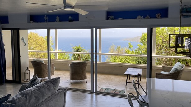 A spacious living area with a large window offering a view of the sea.