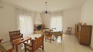 Comedor con una mesa redonda, sillas, una araña y una chimenea.