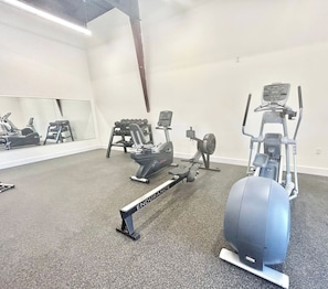 Ein Fitnessraum mit verschiedenen Trainingsgeräten, darunter ein Rudergerät, ein Crosstrainer und ein Fahrradergometer.