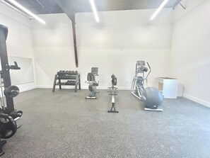 Une salle de sport équipée de matériel de musculation, de machines de cardio et d’un support à squats.