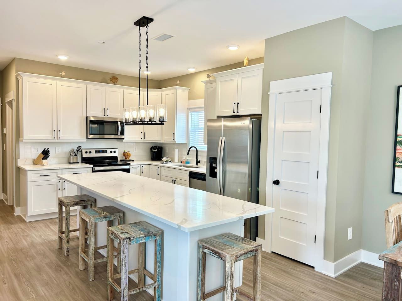 A modern kitchen with white cabinets, stainless steel appliances, and a central island with stools.
