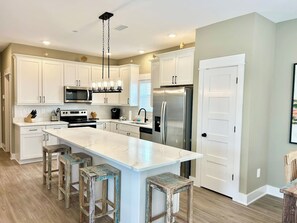A modern kitchen with white cabinets, stainless steel appliances, and a central island with stools.