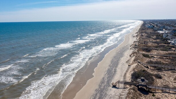 A coastal beach with a sandy shoreline, wooden boardwalks, and residential buildings along the edge. - CHIll IN! Central to Everything! Steps to Beach! (Corolla)