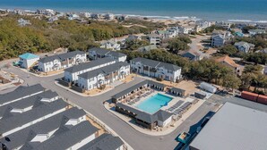 A residential area with a large swimming pool, multiple houses, and a beach in the background. - CHIll IN! Central to Everything! Steps to Beach! (Corolla)