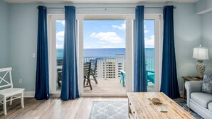 A room with a view of the ocean, a balcony with chairs, and a wooden table. - Ocean View-Gym-Pools-Restaurants - LTW 1517 (Panama City Beach)