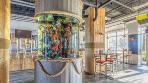A restaurant with a large aquarium centerpiece, wooden walls, and modern seating. - Ocean View-Gym-Pools-Restaurants - LTW 1517 (Panama City Beach)
