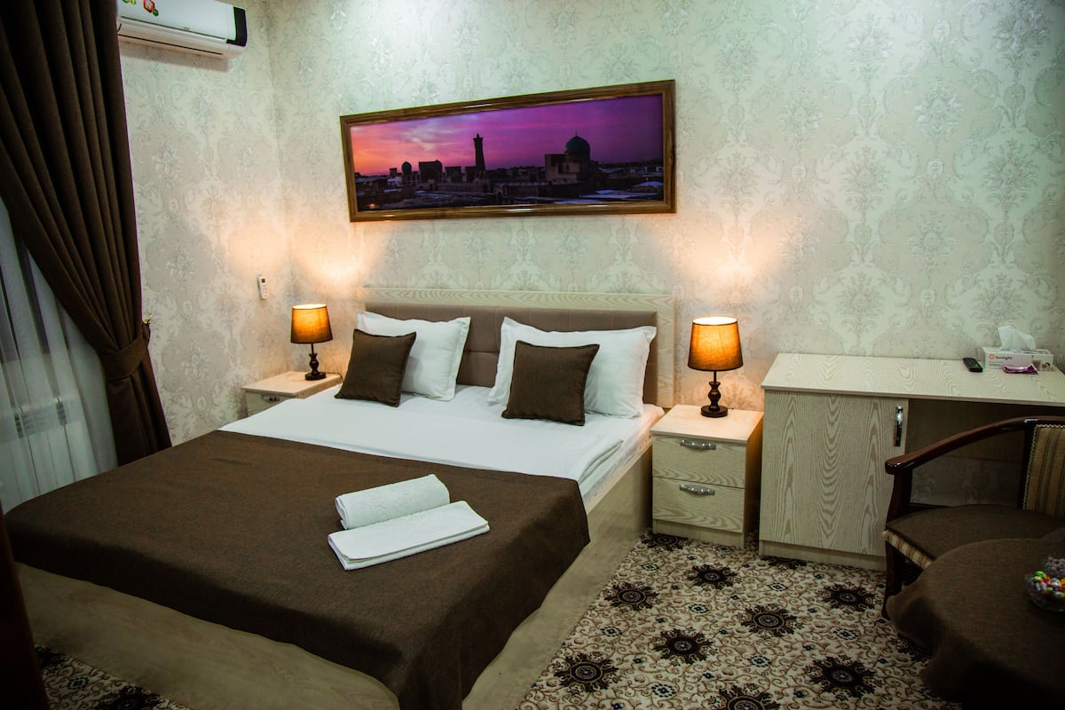 A hotel room with a bed, two bedside tables, a desk, and a chair.