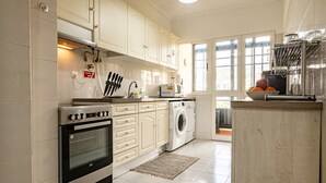 A kitchen with white cabinets, a stove, a washing machine, and a sink. - GuestReady - Family-Friendly Haven in Funchal (Funchal)