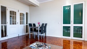 A modern kitchen with white cabinetry, a dining area with a table and chairs, and a glass coffee table with magazines and a teapot. - GuestReady - Family-Friendly Haven in Funchal (Funchal)