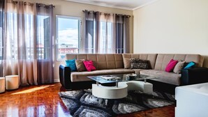 A living room with a beige sofa, a glass coffee table, and a patterned rug. - GuestReady - Family-Friendly Haven in Funchal (Funchal)