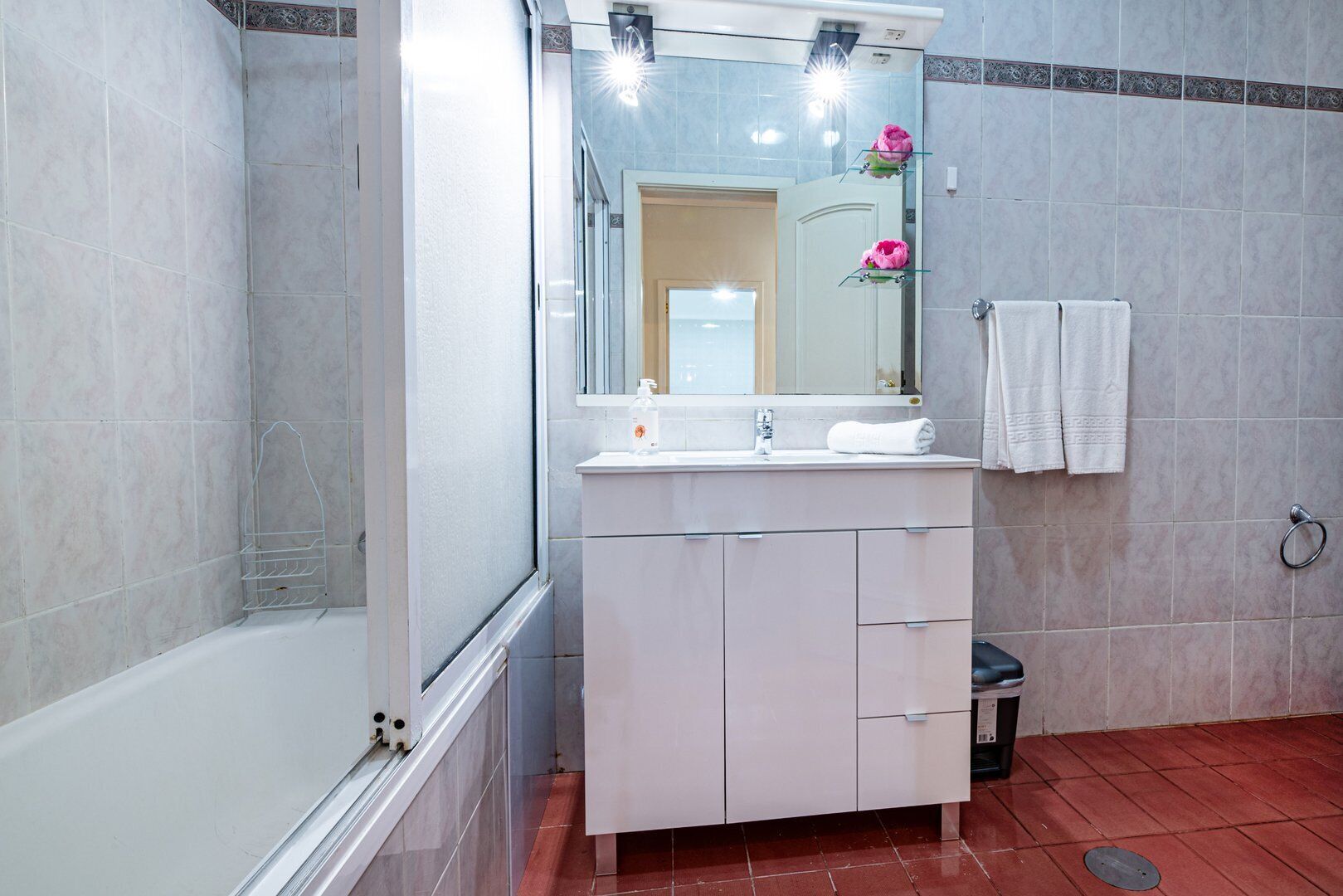 Un baño con una bañera, un lavabo con espejo y un inodoro.
